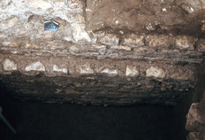 Partie de l'élévation et des fondations (en léger débord) du mur de façade de l'amphithéâtre dans son état du IIe siècle. Le mur est construit en pierres de petit appareil, liées au mortier de chaux.