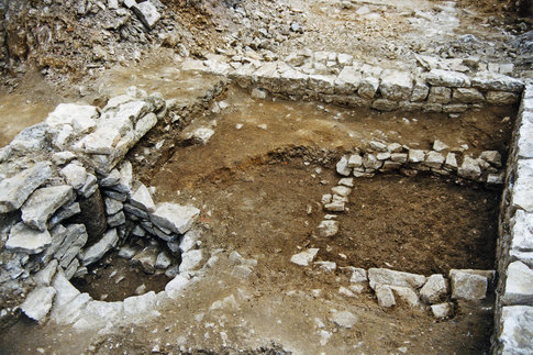 Vue d'une cave m&eacute;di&eacute;vale situ&eacute;e &agrave; l'arri&egrave;re d'une maison qui bordait la place Bacchus.  Une fosse ma&ccedil;onn&eacute;e quadrangulaire et un puits y sont am&eacute;nag&eacute;s. On distingue un fragment de colonne antique r&eacute;employ&eacute; dans le parement du puits, contre le mur de la cave. &copy; S. Cantrelle, Inrap