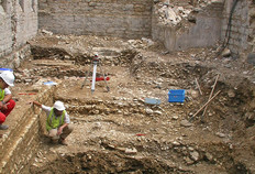 Vue du sondage en cours en 2006.  Les niveaux de voie antique se superposent entre les murs d'une cave moderne.