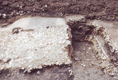 Sol antique en cours de fouille.  On peut voir une superposition de sols en terrazzo, dont la surface liss&eacute;e compos&eacute;e de mortier de chaux et de petits &eacute;clats calcaires repose sur un radier de pierres grossi&egrave;res.