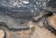 Deux fours de potier gaulois de la fin de La Tène finale ou du début de l'époque romaine creusés successivement, à faible distance. De celui de gauche (le premier) n'est plus visible que le canal annulaire de la chambre inférieure, dans laquelle circulait l'air chaud, et le pilier central qui soutenait la sole (la mire de 1 m donne l'échelle). Celui de droite (le deuxième) présente une sole perforée conservée, sur laquelle étaient disposés les pots à cuire, couverts pendant la cuisson ; la couverture n'est pas conservée.