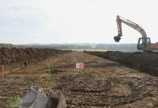 Vue du d&eacute;capage du site &agrave; la pelle m&eacute;canique.  L'axe de la future canalisation de gaz est indiqu&eacute; par le piquet vert.  Le Camp Capron, Marieux (Somme), 2012.&nbsp;