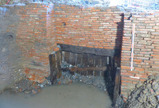 Mur de chemisage de la contrescarpe du fossé Ce mur était destiné à renforcer la paroi orientale du fossé dans un secteur où ce dernier recoupait un paléochenal ancien comblé par différents niveaux de graviers.Un aménagement spécifique de poteaux en bois (photo) permettait à l'eau du paléochenal de s'écouler dans le fossé. Station de métro François-Verdier – ligne C, Toulouse, 2025. © Laurent Grimbert, Inrap