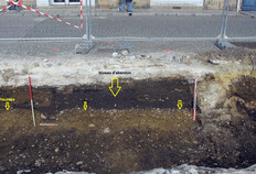 Coupe nord de la tranchée de l'angle nord-ouest de la place. On y voit le niveau de chaussée d'époque romaine bien plan recouvert par une couche de terre noire correspondant au niveau d'abandon. Place de la Mairie, Rennes (Ille-et-Vilaine), 2022 © Dominique Pouille, Inrap