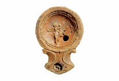 Lampe &agrave; huile fabriqu&eacute;e dans les ann&eacute;es 70/120 apr&egrave;s J.-C. et trouv&eacute;e dans un puits antique. Le m&eacute;daillon est d&eacute;cor&eacute; d'un amour tenant une corbeille haute, le bras droit lev&eacute; vers un arbre pour cueillir des fruits.  12-14 rue L&eacute;opold Morice, 24 avenue Georges Pompidou &agrave; N&icirc;mes (Gard), 2015.  &copy; Bertrand Houix, Inrap