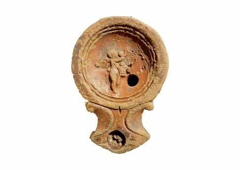 Lampe &agrave; huile fabriqu&eacute;e dans les ann&eacute;es 70/120 apr&egrave;s J.-C. et trouv&eacute;e dans un puits antique. Le m&eacute;daillon est d&eacute;cor&eacute; d'un amour tenant une corbeille haute, le bras droit lev&eacute; vers un arbre pour cueillir des fruits.  12-14 rue L&eacute;opold Morice, 24 avenue Georges Pompidou &agrave; N&icirc;mes (Gard), 2015.  &copy; Bertrand Houix, Inrap 