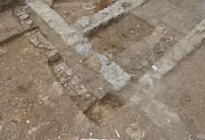 Vue d'un angle sud-ouest de l'enclos ma&ccedil;onn&eacute; situ&eacute; dans la partie est de l'emprise. Il est ponctuellement &eacute;pierr&eacute; et recoup&eacute; par la fondation d'une maison contemporaine. Les murs de l'enclos se distinguent par leur construction en pierres, tandis que les fondations contemporaines se caract&eacute;risent par l'abondant usage de b&eacute;ton gris clair.  1 bis rue de l'Abattoir, N&icirc;mes (Gard), 2022  &copy; Sarah Beiger, Julie Grimaud, Inrap