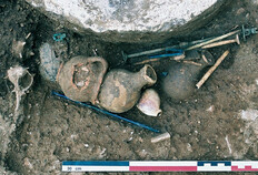 D&eacute;p&ocirc;t d'objets dans la tombe &agrave; cr&eacute;mation d'un homme adulte, 25-75 apr&egrave;s J.-C. Le d&eacute;p&ocirc;t comprend des instruments de filage en os (quenouilles, fuseaux), peut-&ecirc;tre offerts au d&eacute;funt, et des objets pouvant &ecirc;tre attribu&eacute;s &agrave; une activit&eacute; de gu&eacute;risseur (broyeur en bronze orn&eacute; de protom&eacute;s de canid&eacute;s, strigiles miniatures et agitateur en verre, pyxide en os, amulette en cristal de roche, coquillages - murex et porcelaine - fibule &agrave; t&ecirc;te de M&eacute;duse en bronze).  78 avenue Jean-Jaur&egrave;s, N&icirc;mes (Gard), 2003.  &copy; Yves Manniez, Inrap
