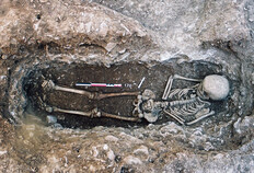 Inhumation d'un enfant d&eacute;c&eacute;d&eacute; &agrave; l'&acirc;ge de 7-8 ans, 150-200 apr&egrave;s J.-C. Le d&eacute;funt a &eacute;t&eacute; d&eacute;pos&eacute; dans une fosse ferm&eacute;e &agrave; l'origine par une couverture en bois reposant sur un ressaut dans la paroi et surmont&eacute;e par un amas de pierres qui devait signaler la tombe en surface.  78 avenue Jean-Jaur&egrave;s, N&icirc;mes (Gard), 2003.  &copy; Val&eacute;rie Bel, Inrap