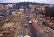 Vue de la fouille en regardant en direction de la Tour Magne. &Agrave; droite le chantier de la tr&eacute;mie d'acc&egrave;s du parking o&ugrave; les arch&eacute;ologues n'ont pas pu faire d'observation.  Place Jules-Guesde, N&icirc;mes (Gard), 1987  &copy; Marc C&eacute;li&eacute;, Inrap
