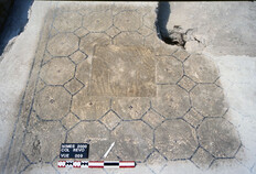 Dans la grande pi&egrave;ce 1, le sol en b&eacute;ton calcaire pr&eacute;sente un canevas d'octogones orn&eacute;s de petites croisettes centrales, sorte de fleurettes de tesselles rouges et noires. Le sol enserre une dalle de calcaire scellant l'ouverture du puits utilis&eacute; ant&eacute;rieurement.  Coll&egrave;ge R&eacute;volution, N&icirc;mes (Gard), 2000  &copy; Michel Piskorz, Inrap