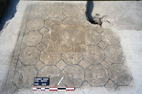 Dans la grande pi&egrave;ce 1, le sol en b&eacute;ton calcaire pr&eacute;sente un canevas d'octogones orn&eacute;s de petites croisettes centrales, sorte de fleurettes de tesselles rouges et noires. Le sol enserre une dalle de calcaire scellant l'ouverture du puits utilis&eacute; ant&eacute;rieurement.  Coll&egrave;ge R&eacute;volution, N&icirc;mes (Gard), 2000  &copy; Michel Piskorz, Inrap 