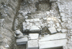 L'emmarchement desservant la plate-forme du temple, Haut Empire&nbsp;  Un redan est am&eacute;nag&eacute; en fa&ccedil;ade du mur de plate-forme qui se trouvait en avant du podium du temple, selon une disposition que l'on retrouve pour l'avant-cour de la Maison Carr&eacute;e. Un massif de ma&ccedil;onnerie signe la pr&eacute;sence d'un escalier qui est confirm&eacute;e par la premi&egrave;re marche en pierre taille, encore en place.  N&icirc;mes, Ancien th&eacute;&acirc;tre (Gard), 1985.  &copy; Francis Cognard, Fonds Arch&eacute;Ofactory