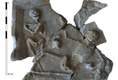 Plaque en marbre orn&eacute;e d'une sc&egrave;ne de banquet provenant du comblement du puits. Elle porte la repr&eacute;sentation en moyen-relief d'un squelette couch&eacute; sur le sol dans l'attitude d'un banqueteur (un canthare dans la main gauche et un vase dans la main droite), faisant face &agrave; un squelette &eacute;chanson qui se tient debout, une lanterne dans la main gauche. Le relief &eacute;voque les pr&eacute;ceptes de l'&eacute;picurisme, particuli&egrave;rement en vogue au Ier si&egrave;cle.  54-56 rue Notre Dame et rue de Beaucaire, N&icirc;mes (Gard), 2011   &copy; Val&eacute;rie Bel, Marie Rochette, Fr&eacute;d&eacute;rique Robin, Inrap